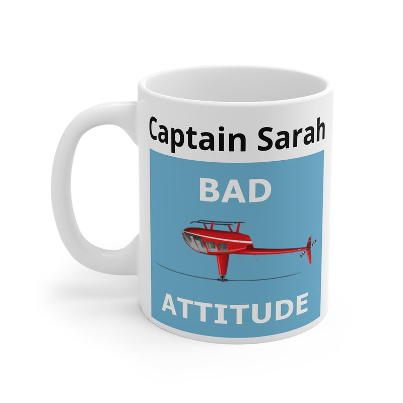 A white ceramic mug with a funny helicopter graphic design featuring a light blue panel, a red helicopter upside down, a custom text section and the text'BAD ATTITUDE'.